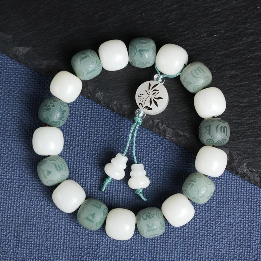 Overhead flat lay of handcrafted bodhi protection bracelet on blue fabric showing natural bead texture and carved mantras
