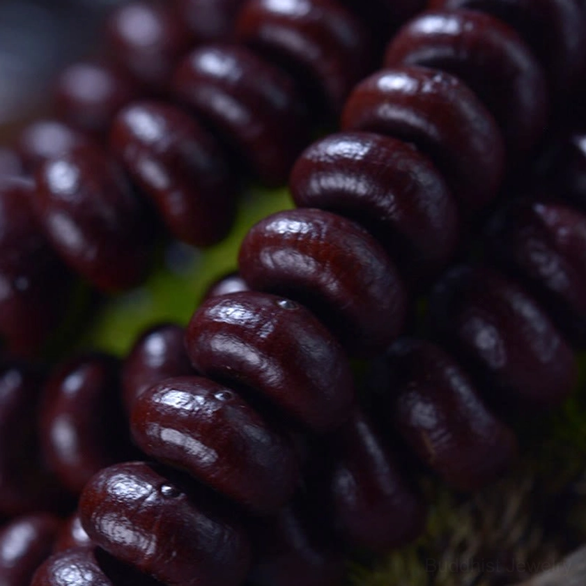 Side angle macro view of purple bodhi seed beads with subtle surface texture and natural patina
