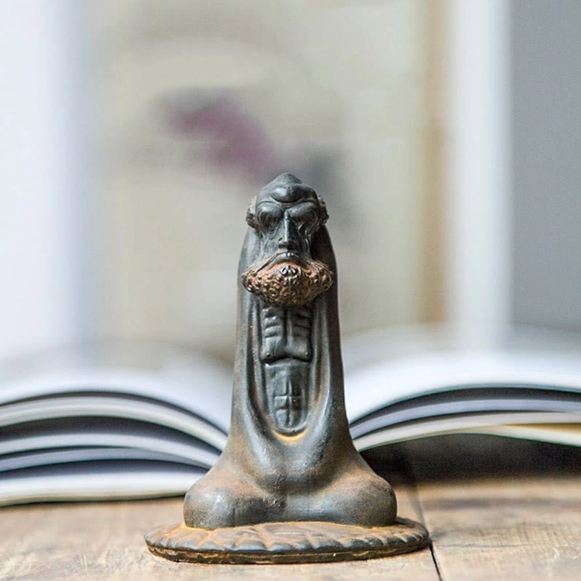 Handmade Bodhidharma meditation statue close-up front with open book background showing facial details