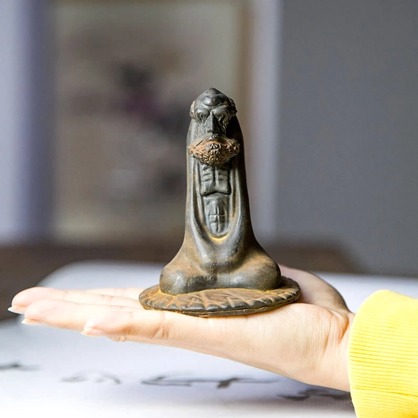 Small Bodhidharma iron powder statue held in hand showing compact size and weathered finish