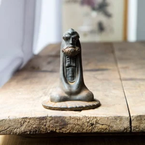 Bodhidharma iron powder resin statue rust version front view on wooden table with antique book