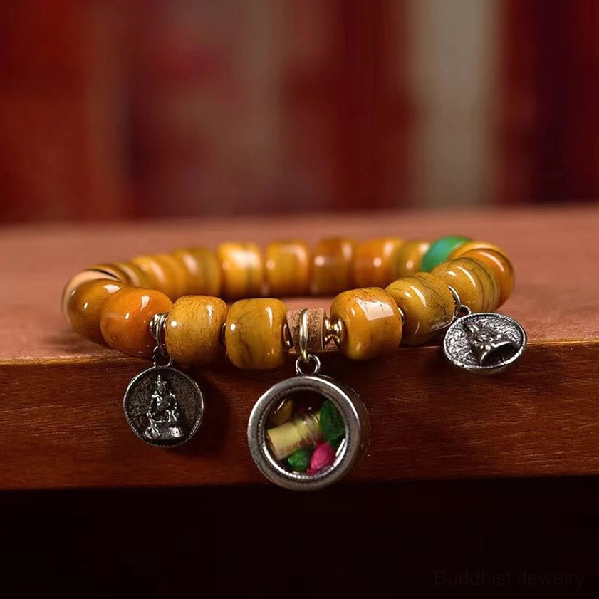 Low angle view of bone bead bracelet with dzi stone, carved fox charm, and multiple metal accents