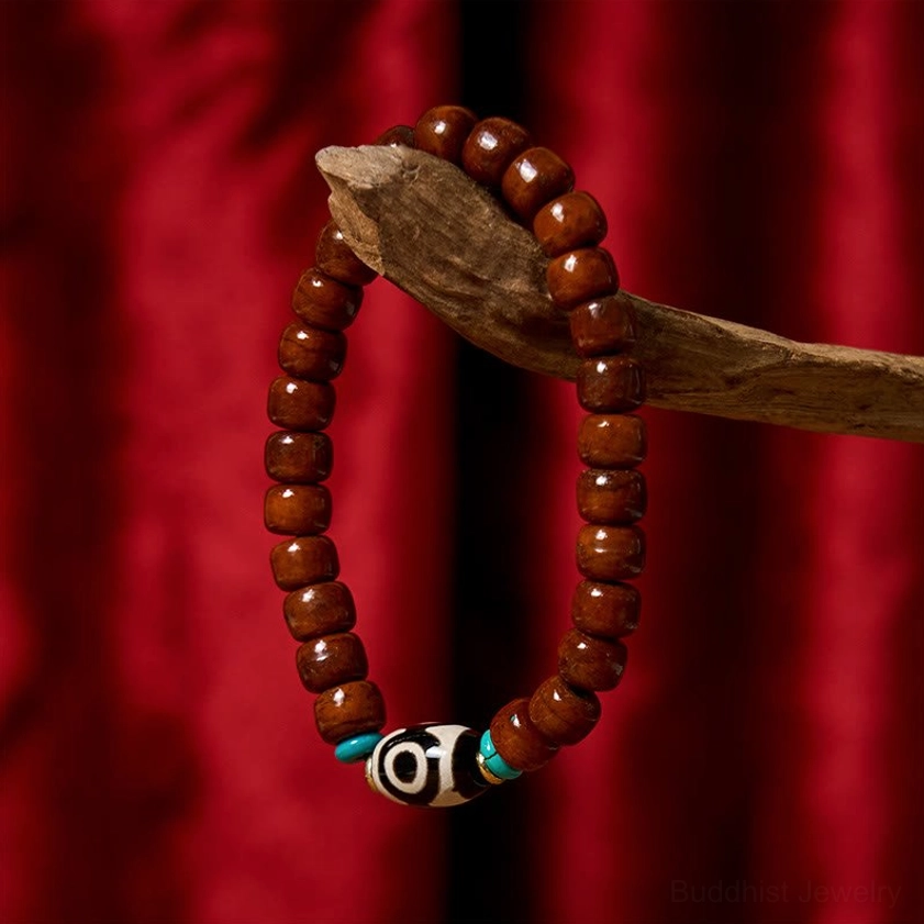 Plain reddish-brown bone bead bracelet with smooth barrel beads on wooden prop with red fabric background