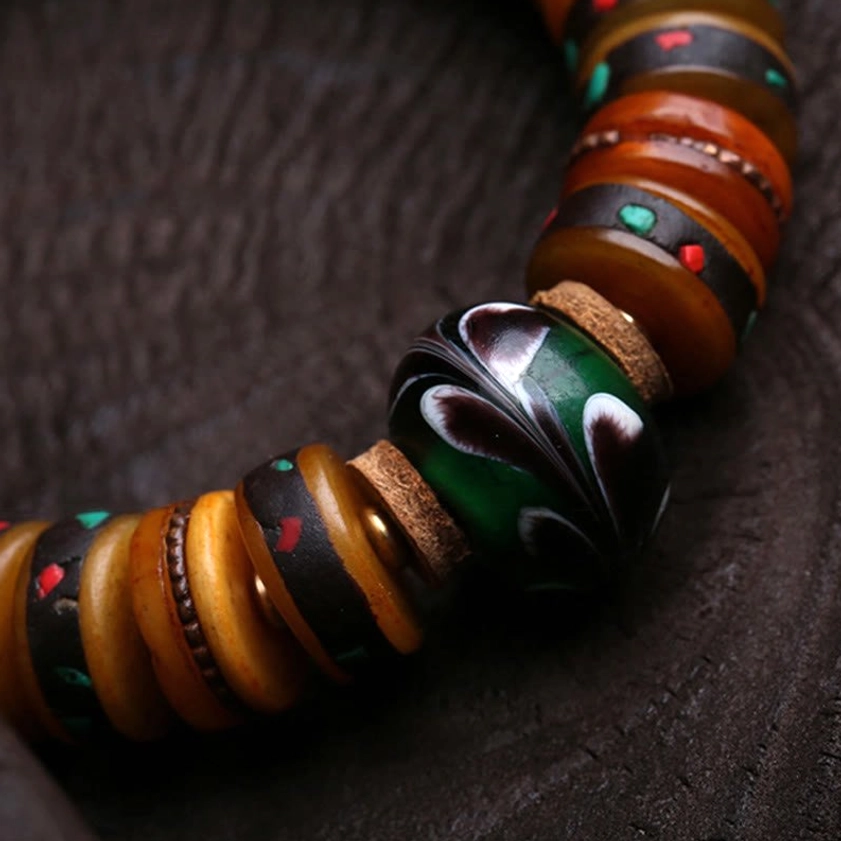 Side view of bone bead bracelet assembly showing swirled glass bead and brown bone discs with green-red accents