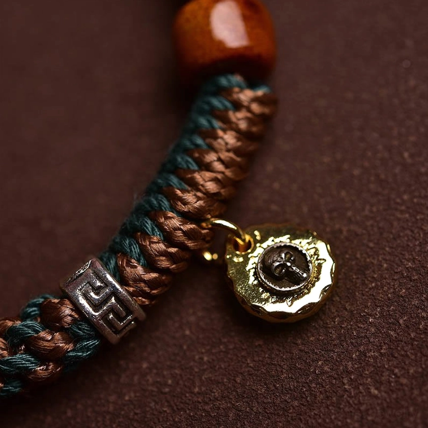 Buddhist bone bead bracelet showcasing natural material quality, artisan craftsmanship, and spiritual symbol metal charm details