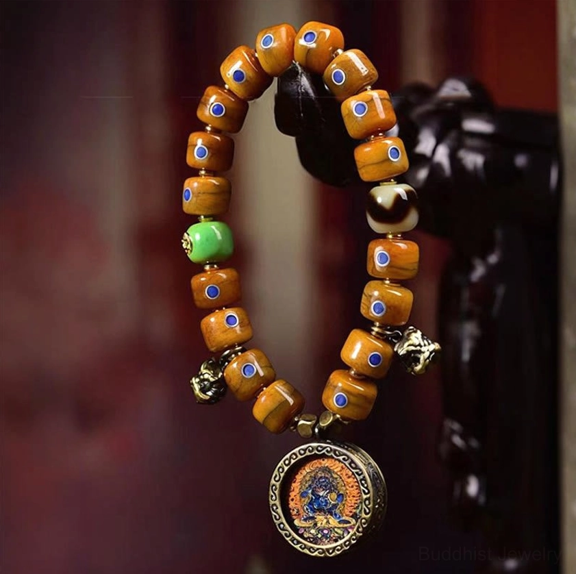 Buddhist bone bead bracelet hanging with lazurite stones and copper bell on dark ornament background
