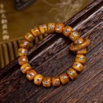 Handcrafted Buddhist bone bead bracelet with lapis lazuli stone and copper accents, overhead view on dark wooden background