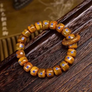 Handcrafted Buddhist bone bead bracelet with lapis lazuli stone and copper accents, overhead view on dark wooden background
