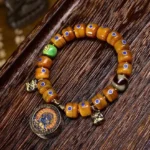 Handcrafted bone bead Buddhist bracelet with lazurite stones and copper bell pendant, overhead view on wooden desk