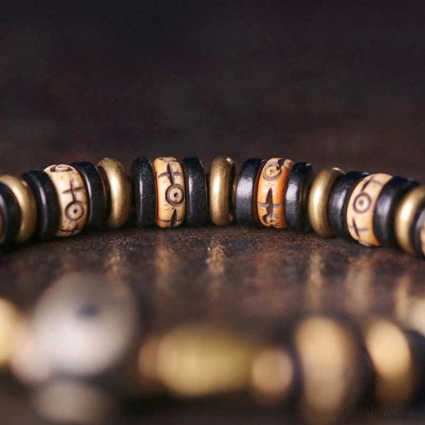 Shallow depth of field close-up of ebony wood Buddhist bracelet showing engraved wooden beads and bronze metal spacers in sharp detail