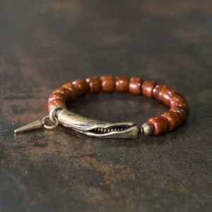 Handcrafted bone beads copper cone pendant strength bracelet displayed overhead on dark rustic metal background, showing brown cylinder beads with antique bronze clasp and spike charm