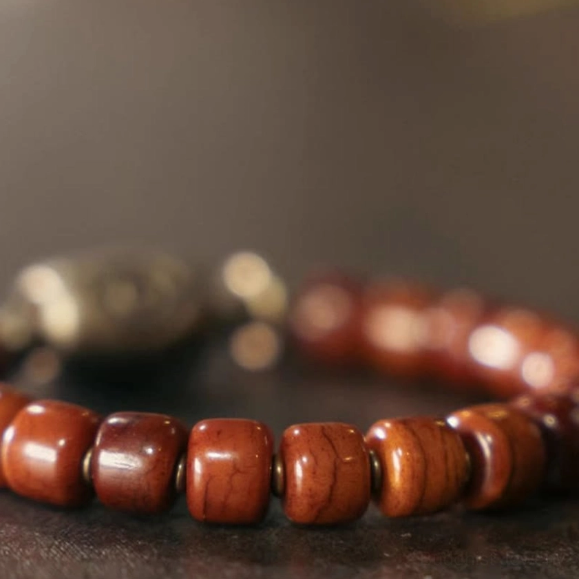 Macro close-up of bone beads Buddhist bracelet showing natural wood grain texture Dzi eye charm and metal spacer beads