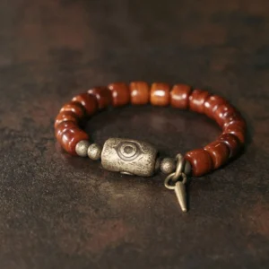 Bone beads Dzi eye copper cone strength bracelet flat lay top-down view with antique bronze charm on vintage desktop