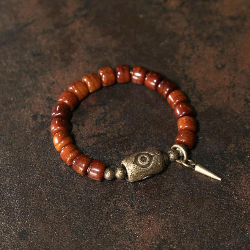 Handmade Buddhist bracelet with bone beads and Dzi eye charm showing copper cone pendant detail from side angle