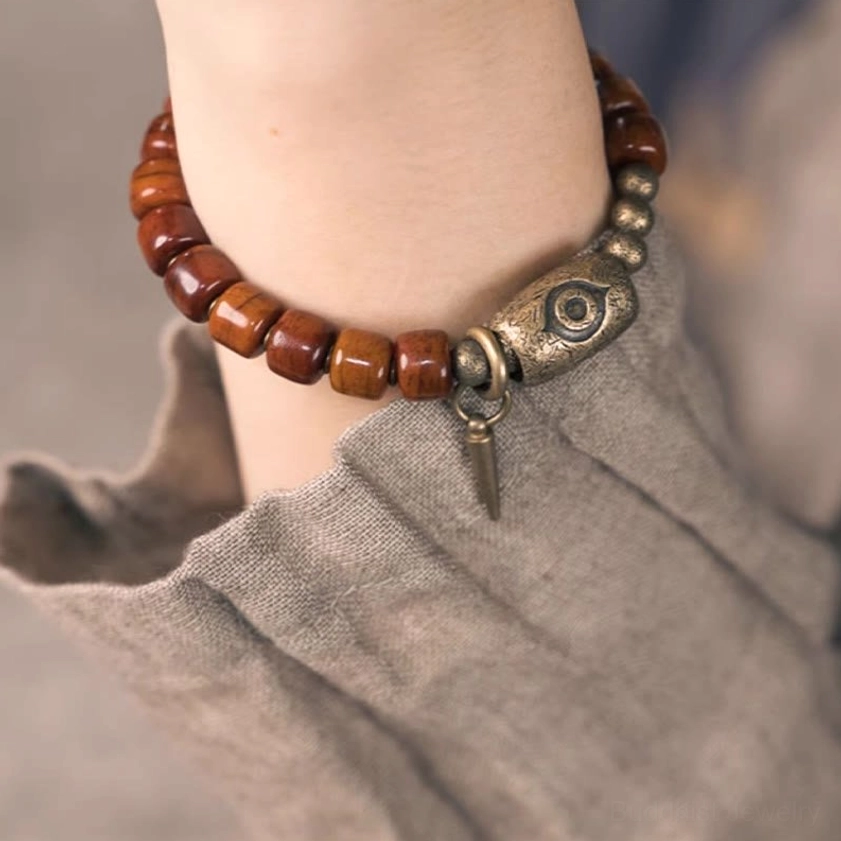 Wrist-mounted bone beads Buddhist bracelet showing elastic band fit and hanging copper cone pendant on linen background