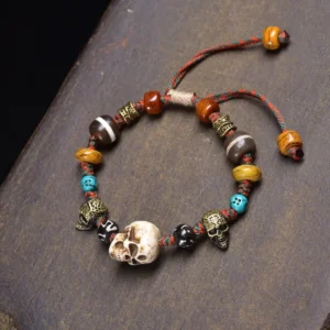 Mixed bone beads skull bracelet with colorful braided cord on dark wooden surface