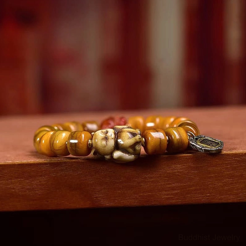 Side view of handmade bone bead bracelet with dzi stone, fox charm, and copper metal pendant