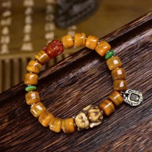 Handcrafted bone bead bracelet with red dzi stone and carved fox charm, overhead view on dark wooden tray