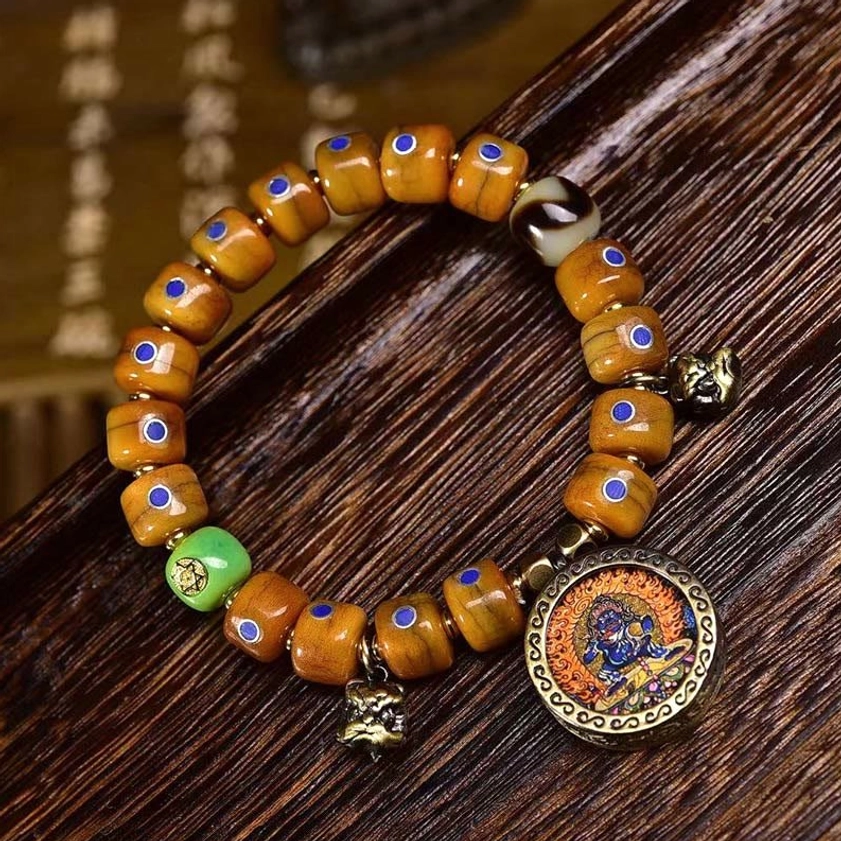 Vintage bone bead mala bracelet with blue lazurite inlays and metal accessories on calligraphy background