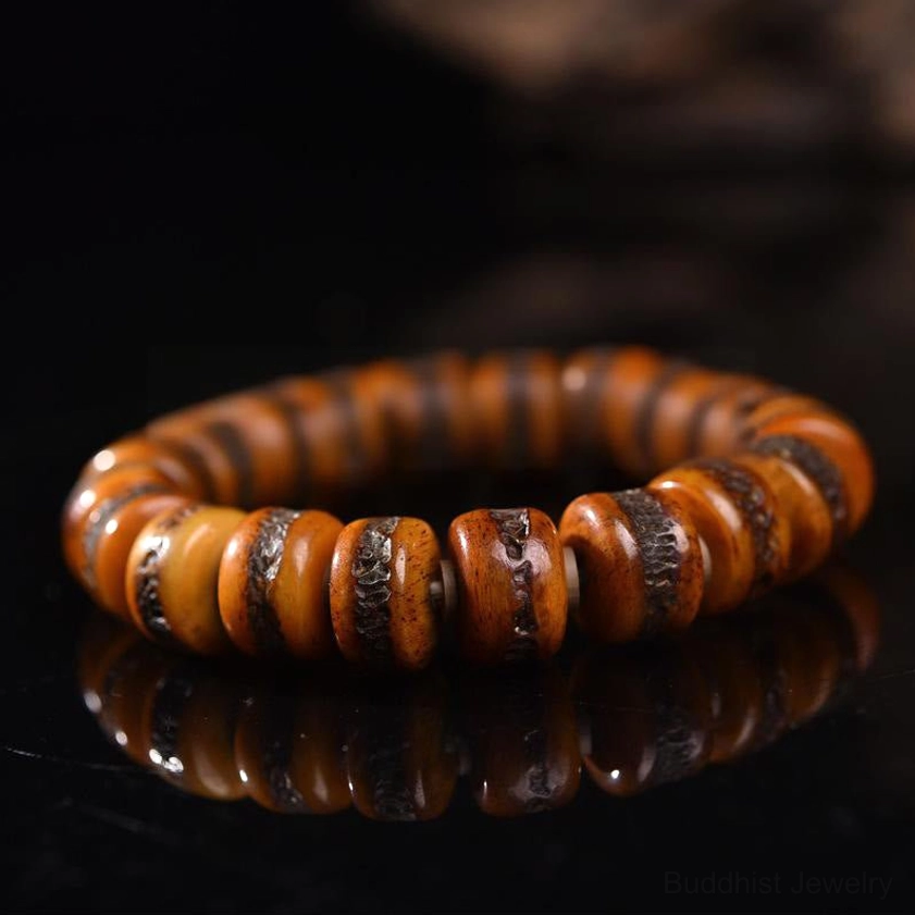 Buddhist bone skull bracelet flat lay showing symmetrical aged bone disc beads – top down view on reflective black surface