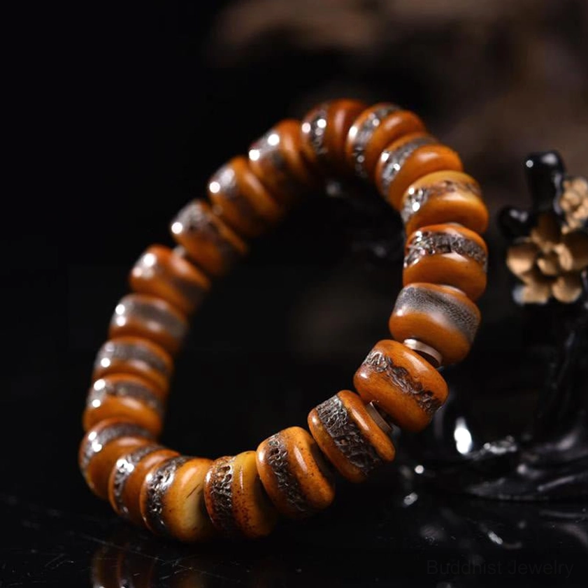Bone skull bracelet side angle view with flat disc beads and copper metal spacers – styled with wooden decorative prop