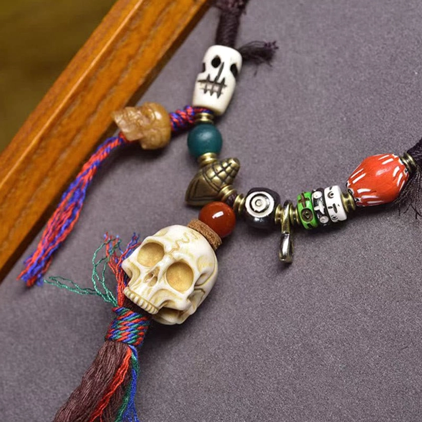 Close-up overhead view of bone skull Buddhist necklace with antique copper ornaments, mixed gemstone beads, and multicolored spiritual tassels