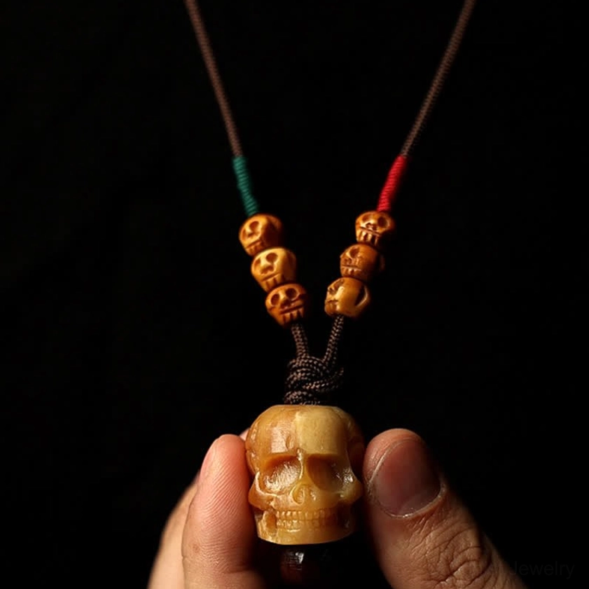 Bone skull pendant held between fingers showing intricate hand-carved details