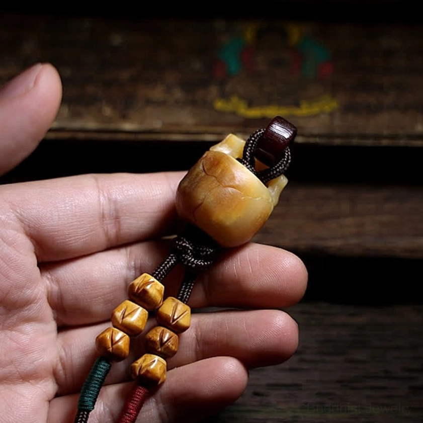 Reverse side view of bone skull pendant with small carved bone beads on wooden background