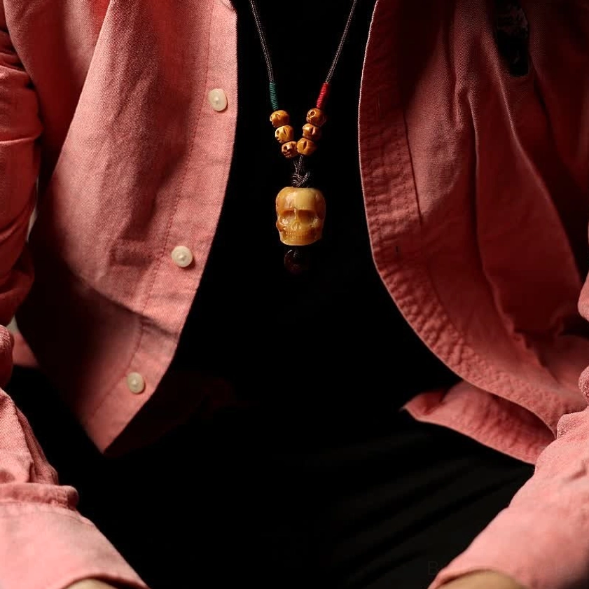 Bone skull necklace worn on chest with casual pink shirt, lifestyle wearable perspective
