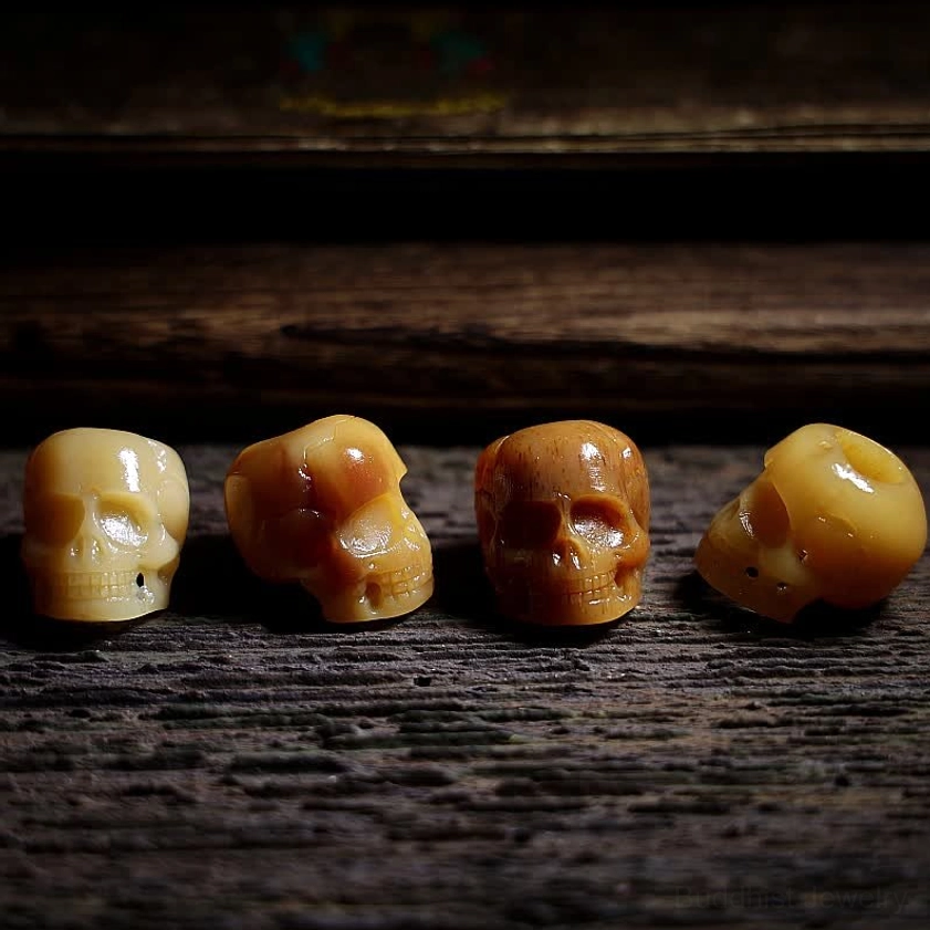 Multiple hand-carved bone skull pendants showing natural color and texture variations