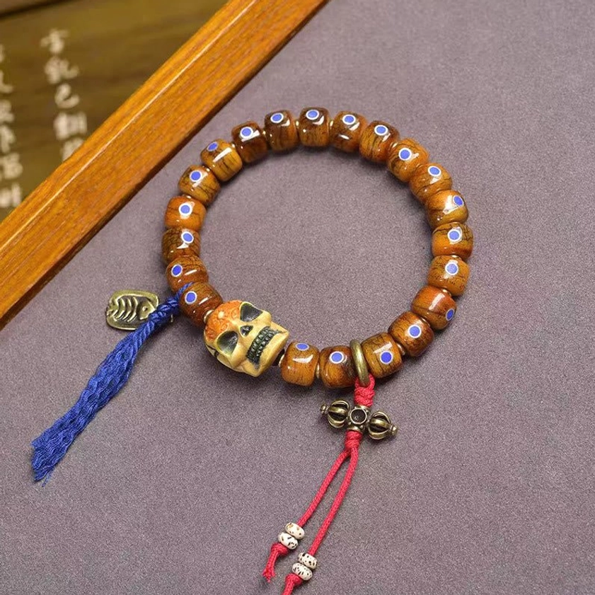 Buddhist bone skull focal bead bracelet overhead view showing intricate inlay work and colorful fabric accents