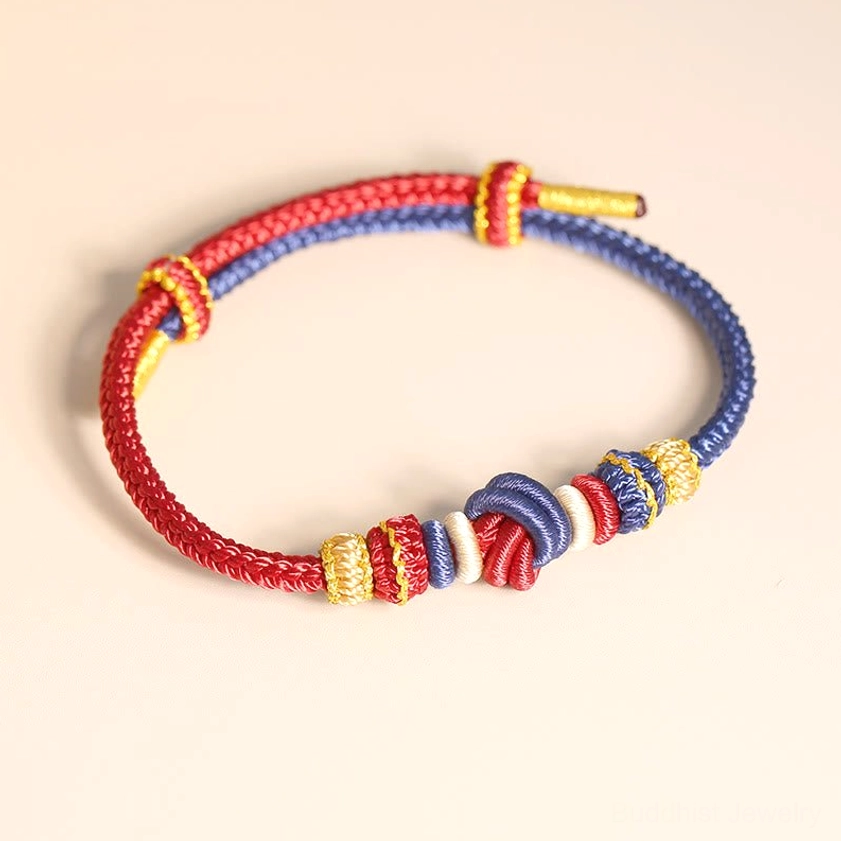 Handcrafted dual-tone braided Buddhist string bracelet with sacred knot design flat lay view