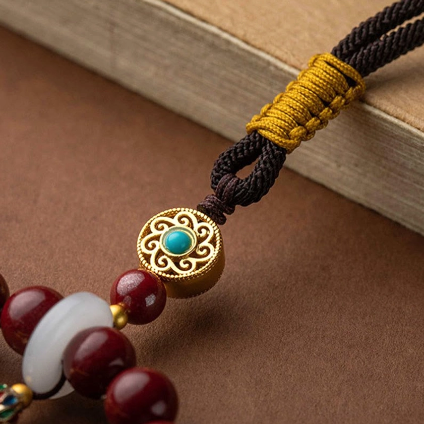 Close-up of braided black cord with enamel gold ornament attachment, adjustable cinnabar ruyi car hanging decoration cord detail