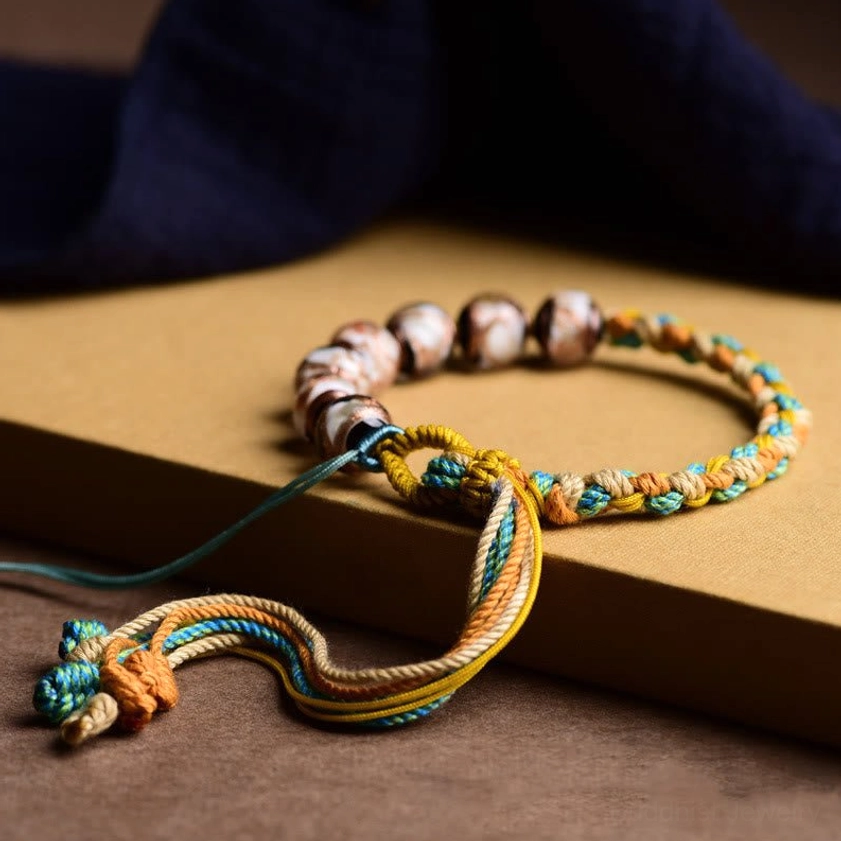 Handcrafted multicolored braided cord bracelet with long decorative tassel on kraft paper