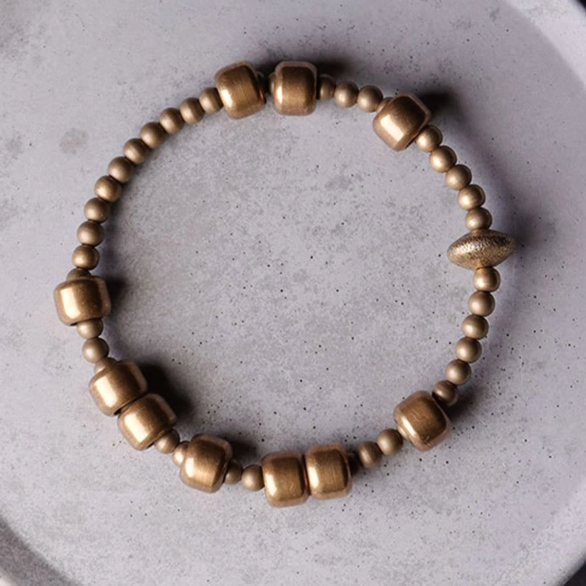 Handmade copper balance bracelet full circle layout on ceramic plate showing textured accent bead design