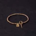 Vintage brass beaded bracelet with Good Luck charm and cone pendant - overhead view showing Buddhist fortune bracelet design
