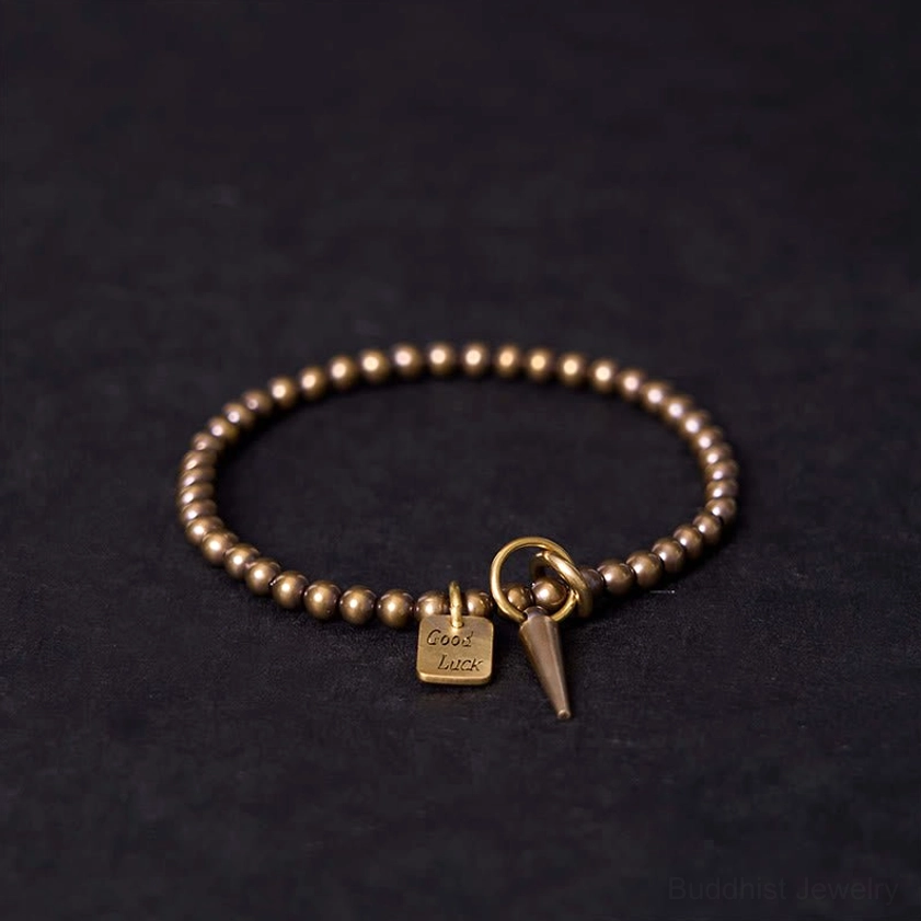 Vintage brass beaded bracelet with Good Luck charm and cone pendant - overhead view showing Buddhist fortune bracelet design