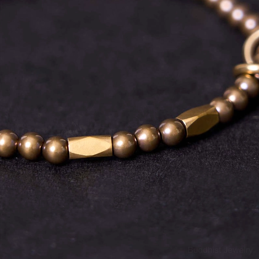 Extreme close-up side view of brass couple bracelet showing flat rectangular accent bead and polished brass finish detail