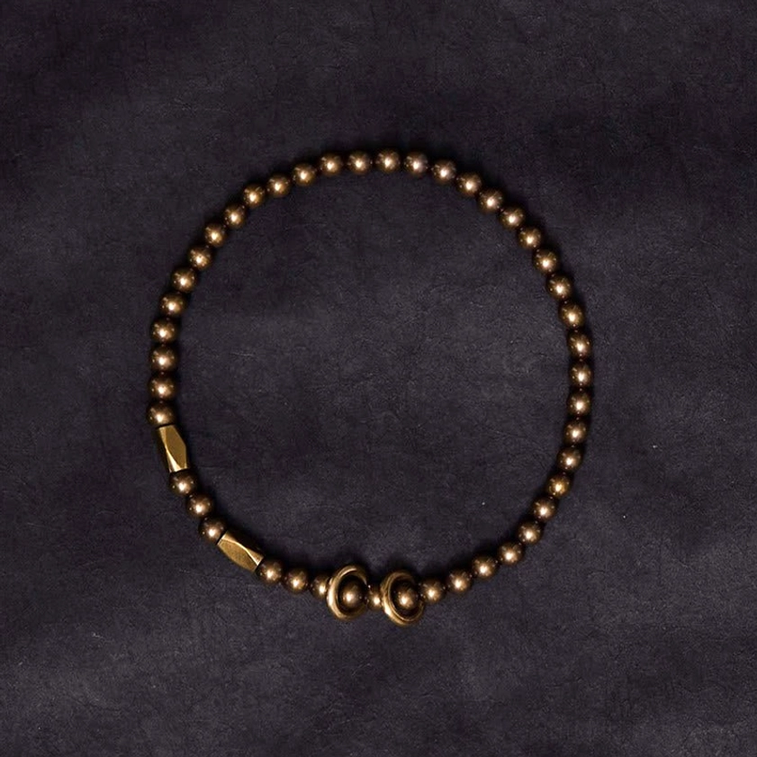 Vintage bronze brass couple bracelet with faceted accent beads and oval toggle clasp on dark fabric background
