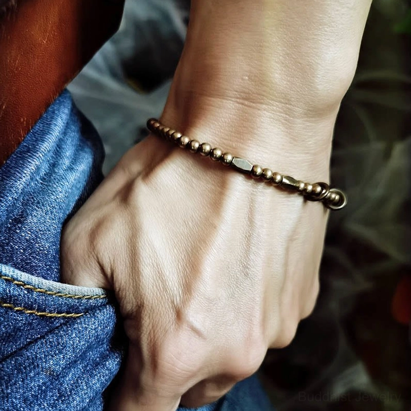 Men's lifestyle photo of brass couple bracelet worn on male wrist with denim, showing mixed bead design in everyday setting