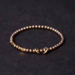 Brass couple bracelet with round matte beads and toggle clasp closure on dark background, shown from above
