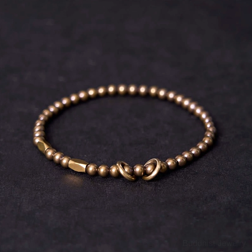 Brass couple bracelet with round matte beads and toggle clasp closure on dark background, shown from above