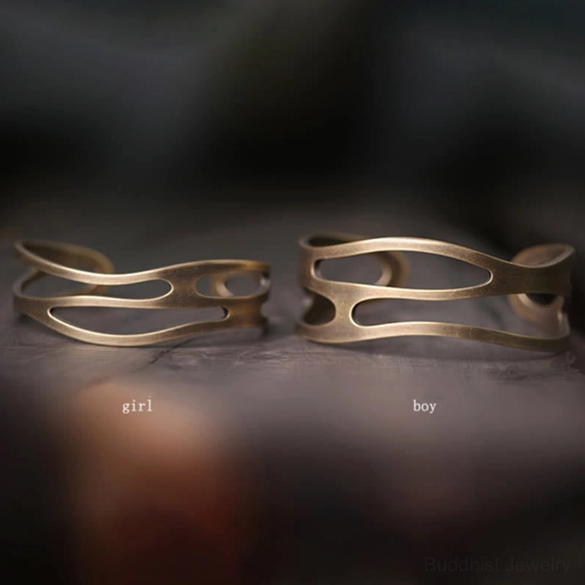 Two types of brass prosperity cuff bracelets flat lay displaying slim cuff and wider double-band designs in antique brass finish