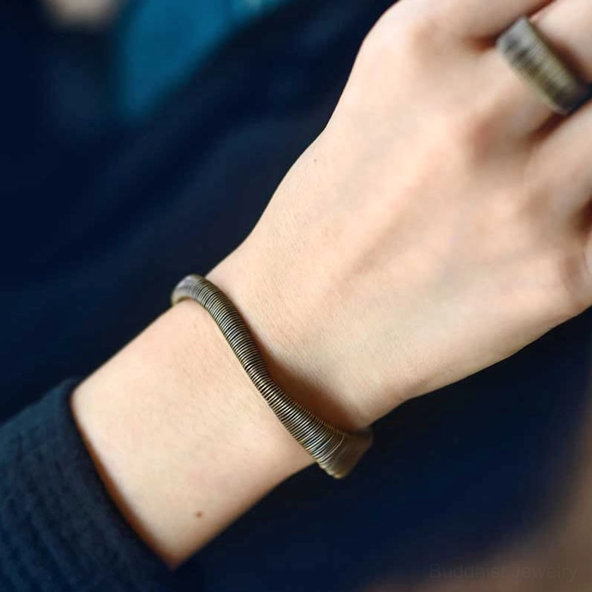 Buddhist brass cuff bracelet detail shot emphasizing handcrafted wire wrapping pattern and artisan quality