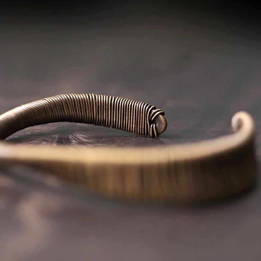 Buddhist energy cuff bracelet low overhead side view with coiled wire end cap and curved open design