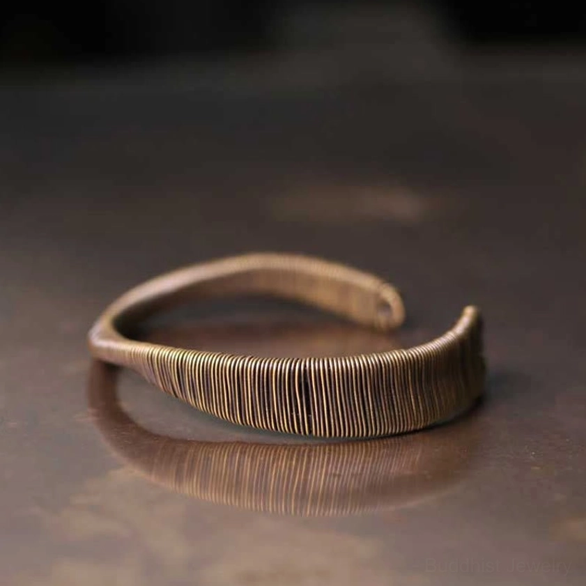 Open cuff bracelet three-quarter side perspective showing dense vertical wire wrapping and reflective metal surface