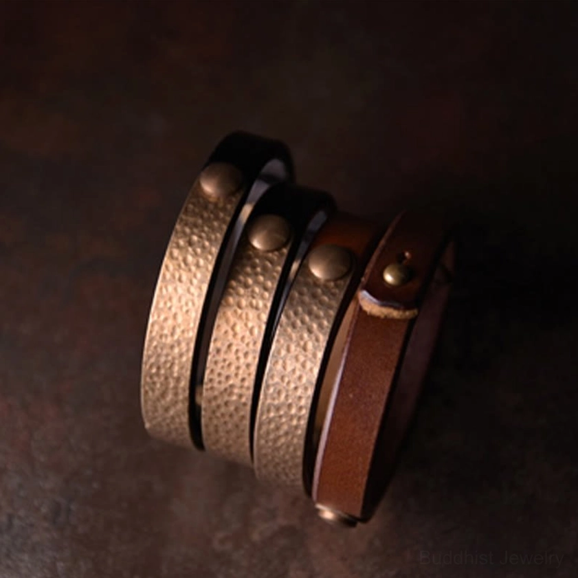Minimalist smooth bronze metal cuff bracelet worn on wrist with grey coat showing everyday style versatility