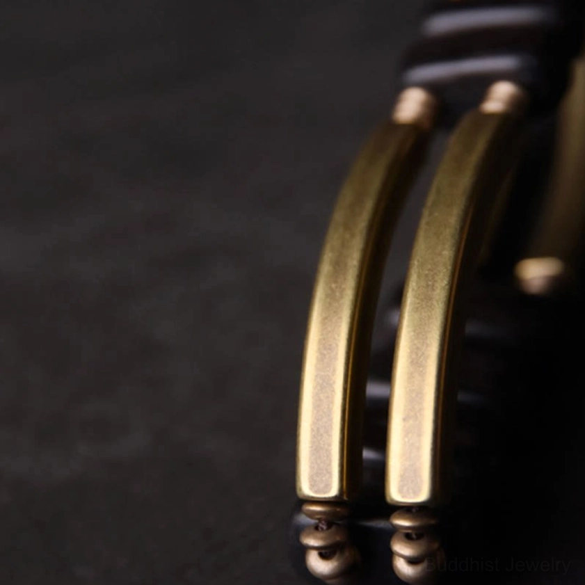Extreme close-up of brushed brass metal connection components on handcrafted Buddhist bracelet