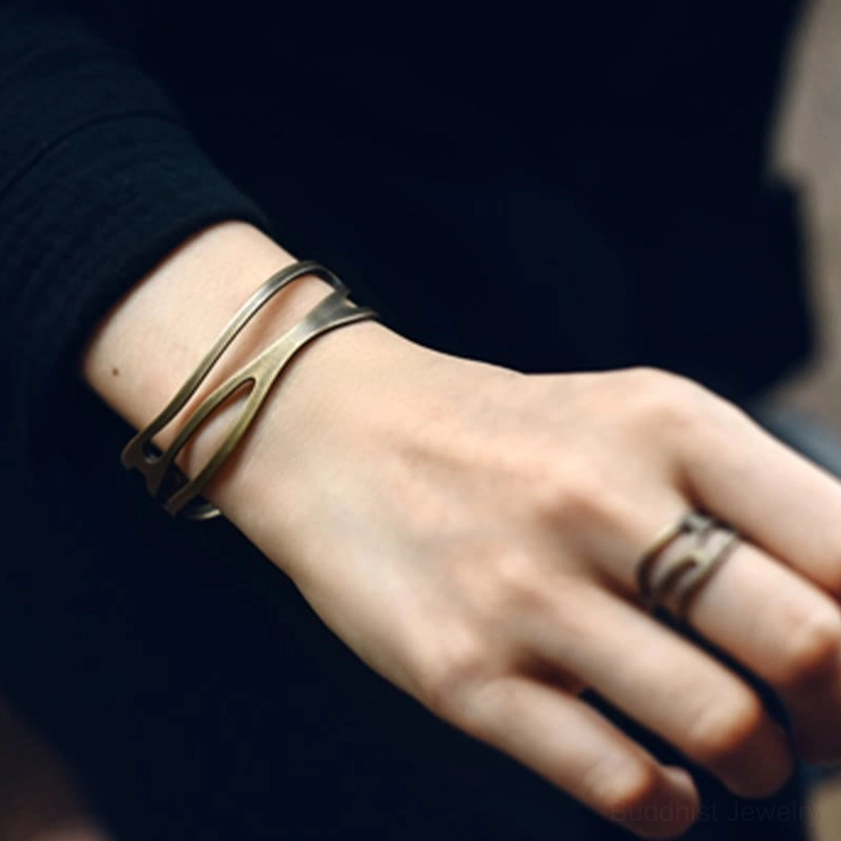 Brass Buddhist cuff bracelet and matching ring set worn on hand and wrist showing stackable design with brushed antique bronze patina