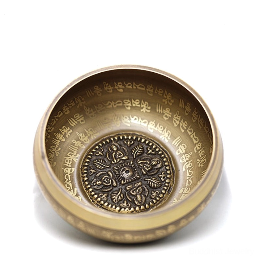 Top-down close-up of singing bowl interior showing carved floral mandala pattern and full engraved Tibetan Buddhist sacred text
